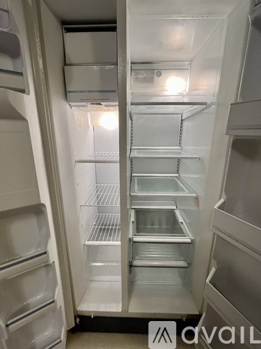A white refrigerator with the door open and shelves inside.