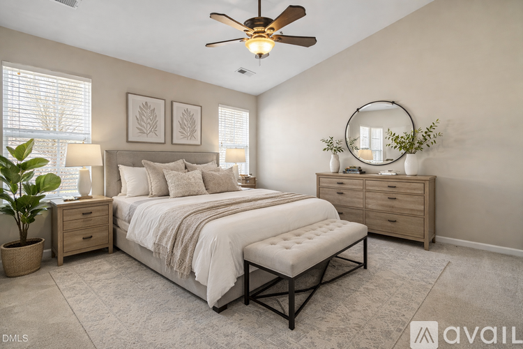 A well-lit bedroom with a large bed, a bench, and a ceiling fan.