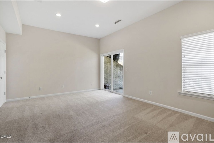 A spacious room with a carpeted floor and a doorway leading to another room.