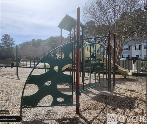 A playground with a green slide and a red pole.
