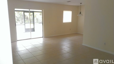A spacious room with tiled flooring and sliding glass doors leading to a balcony.