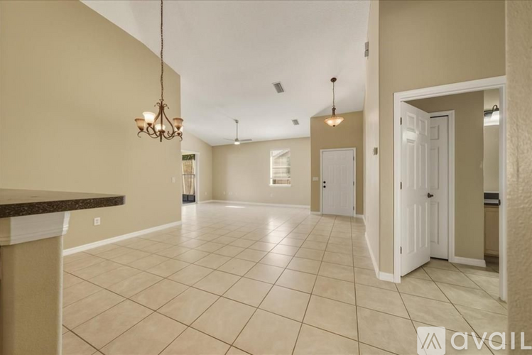 A spacious living room with a chandelier and tiled flooring.