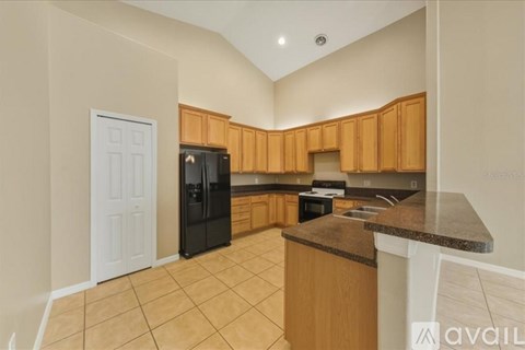 A kitchen with wooden cabinets and a black fridge.