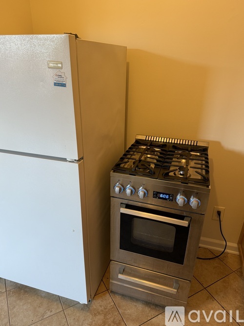 A white refrigerator stands next to a stainless steel stove in a kitchen.
