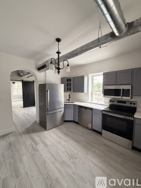 A modern kitchen with stainless steel appliances and a chandelier.