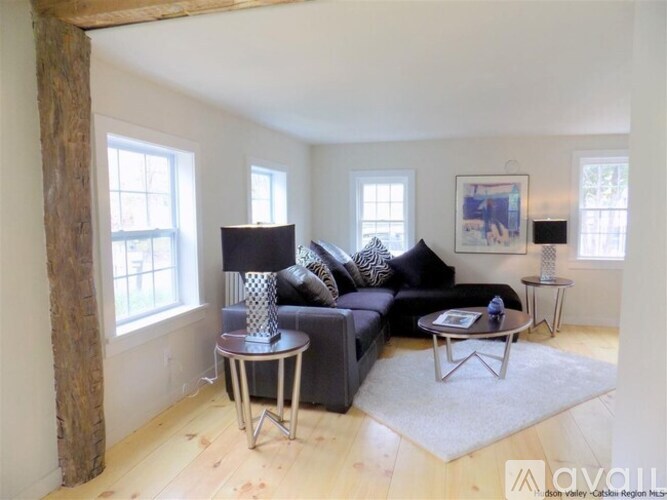 A living room with a black couch, a coffee table, and a lamp.