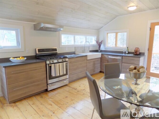 A modern kitchen with wooden floors and a glass dining table.