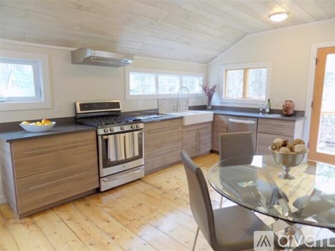 A modern kitchen with wooden floors and a glass dining table.