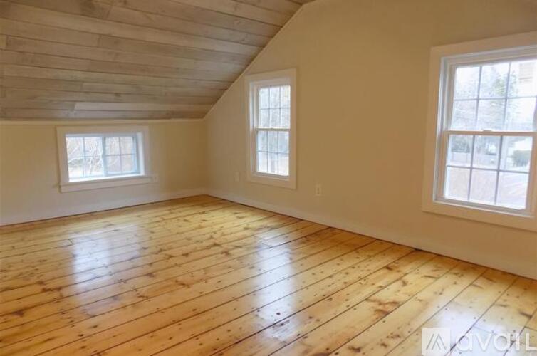A room with wooden floors and two windows.