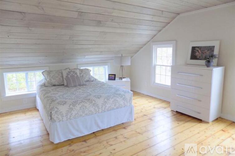 A bedroom with a bed, nightstand, and dresser.