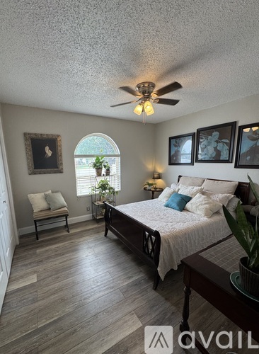 A bedroom with a bed, a chair, and a ceiling fan.