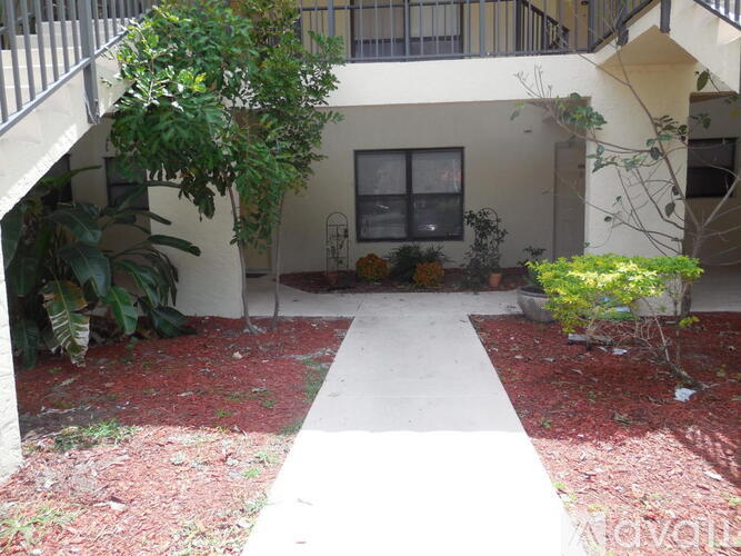 A courtyard with a white pathway and a building in the background.