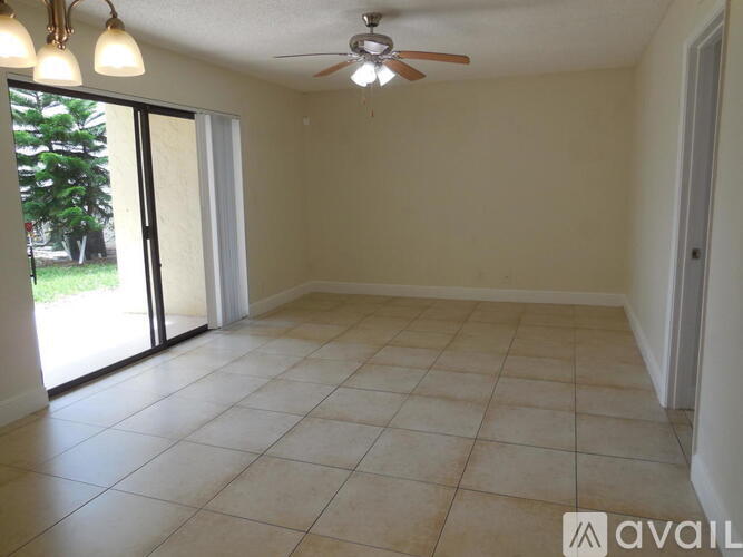 A room with a ceiling fan and sliding glass doors.