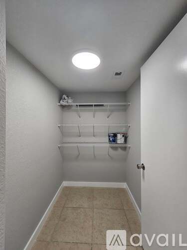 A white hallway with a shelf and a door.