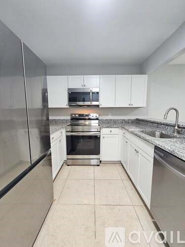 A kitchen with white cabinets and a stainless steel refrigerator.