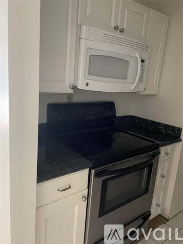 A kitchen with white cabinets and a black countertop.