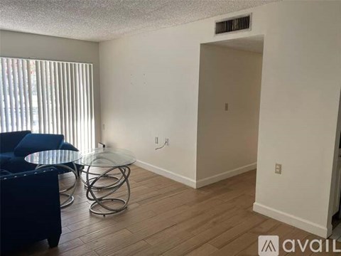 A living room with a blue chair and a glass table.