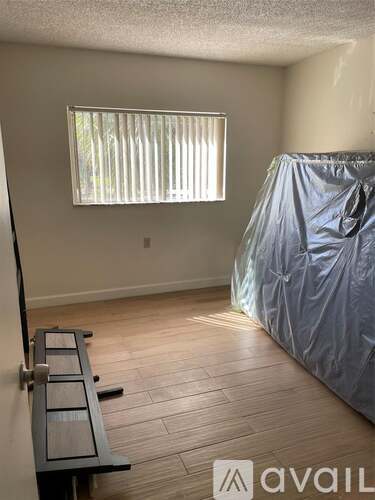 A room with wooden flooring and a window covered with blinds.