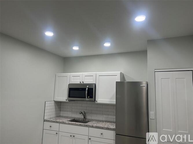 A kitchen with white cabinets and a stainless steel refrigerator.
