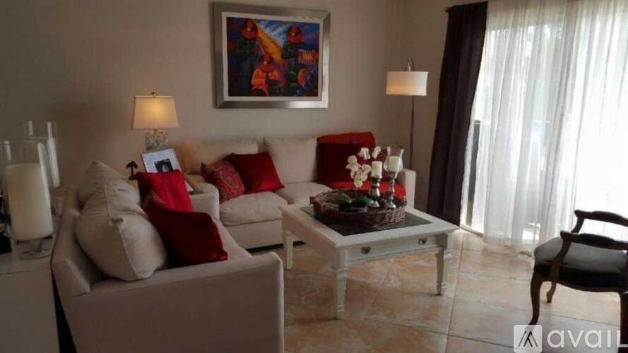 A living room with a grey couch, a coffee table, and a painting on the wall.