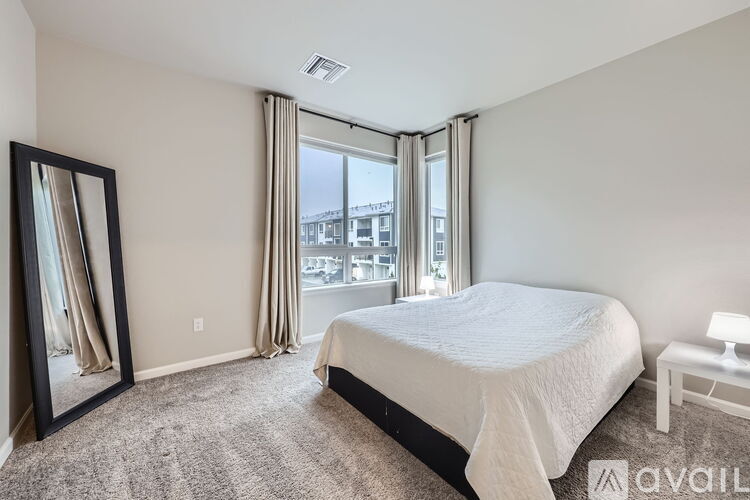 A bedroom with a large bed, a mirror, and a window with curtains.