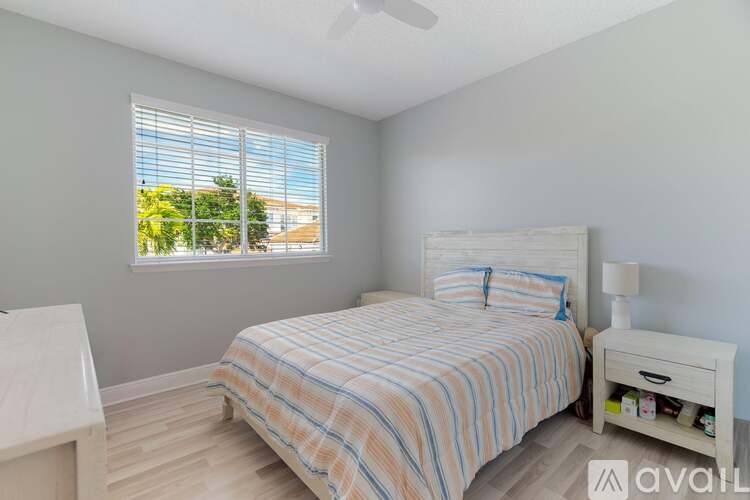 A bedroom with a bed, nightstand, and window with blinds.
