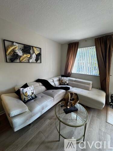 A living room with a white couch and a glass coffee table.