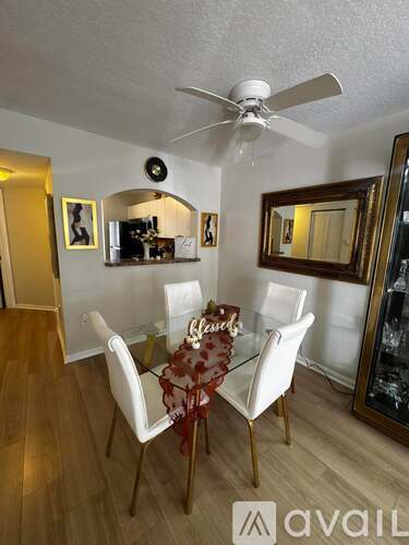 A dining room with a glass table and white chairs.
