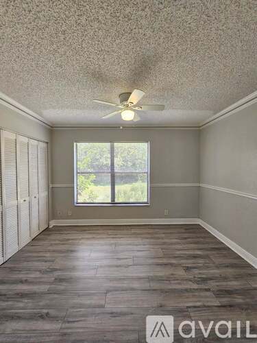 A room with a ceiling fan and a window with blinds.