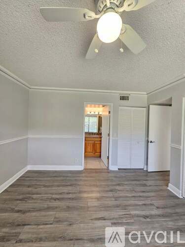 A room with a ceiling fan and wooden flooring.