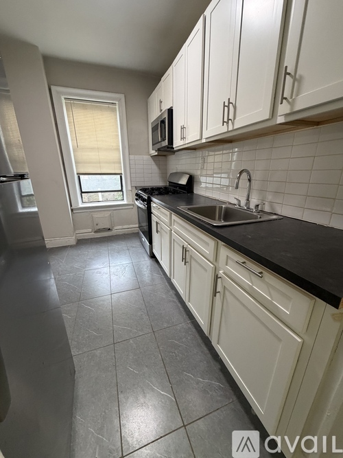 A kitchen with white cabinets and black countertops.