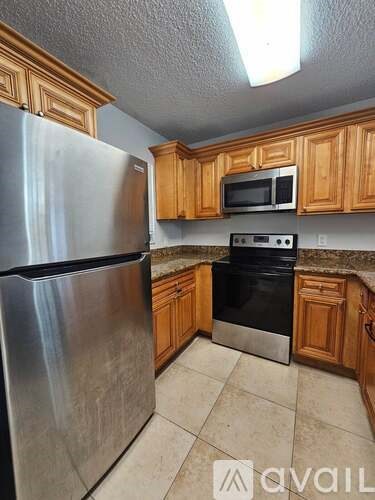 A kitchen with wooden cabinets and a stainless steel refrigerator.