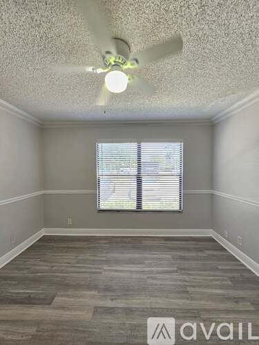 A room with a ceiling fan and a window with blinds.