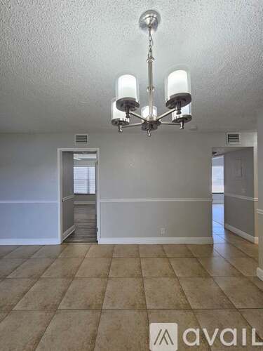 A room with a chandelier and tiled flooring.