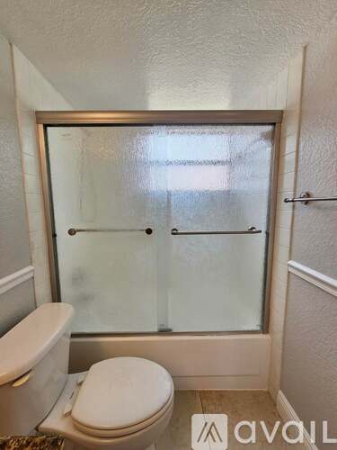 A small bathroom with a toilet and a glass shower door.