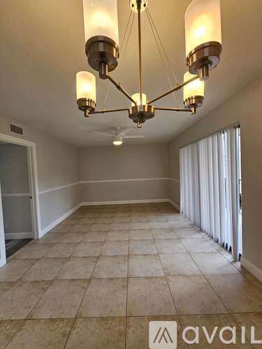 A room with a chandelier and tiled flooring.