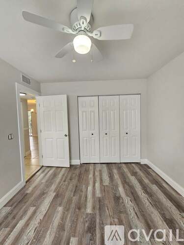 A room with a ceiling fan and wood flooring.