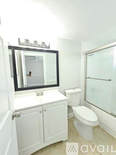 A white bathroom with a toilet, sink, and mirror.