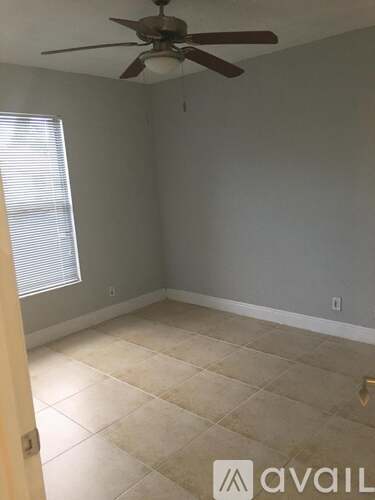 A room with a ceiling fan and a window with blinds.