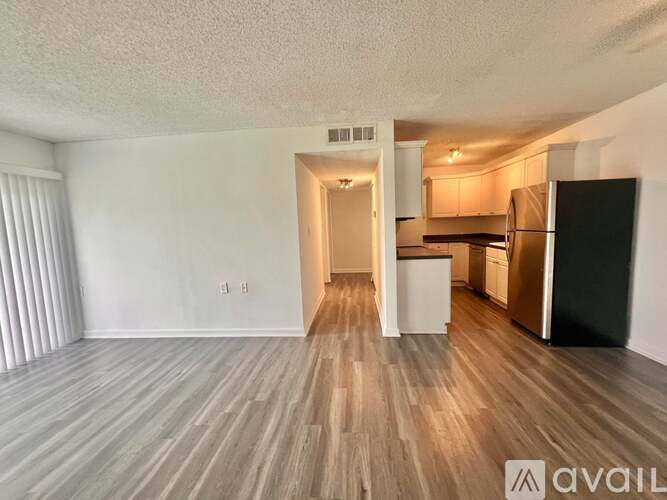 A kitchen area with a refrigerator, cabinets, and a countertop.
