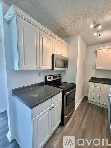 A kitchen with white cabinets and black countertops.
