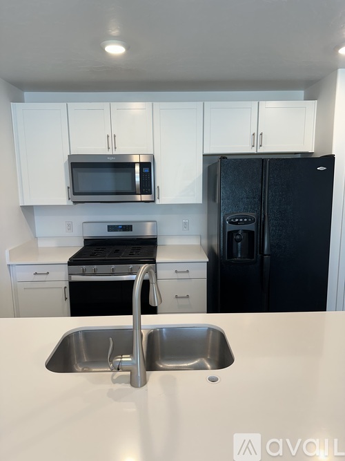 A kitchen with a black refrigerator and white cabinets.