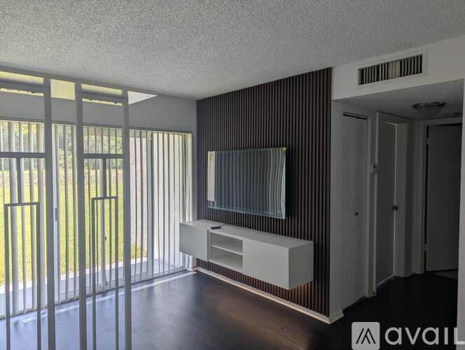 A room with a television and sliding glass doors.