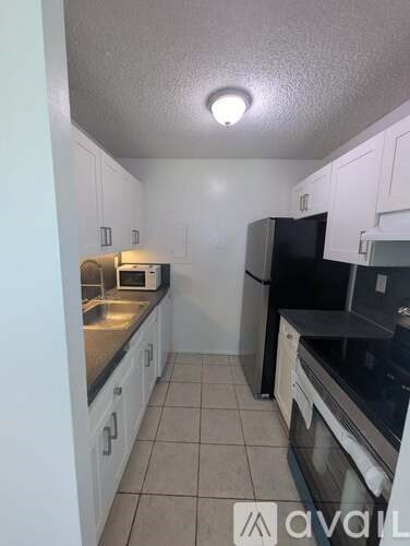 A kitchen with white cabinets and black appliances.
