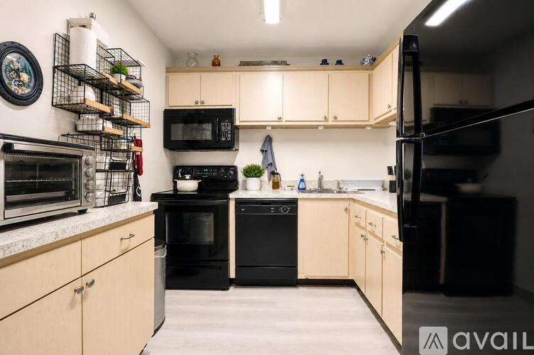 A kitchen with black appliances and wooden cabinets.