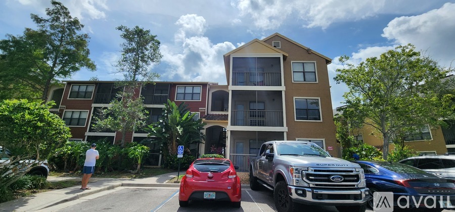 A red car is parked in front of a multi-story apartment building.
