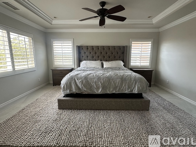 A bedroom with a large bed and a ceiling fan.
