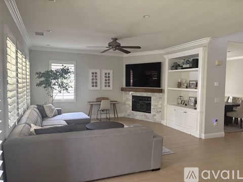 A living room with a grey couch and a fireplace.