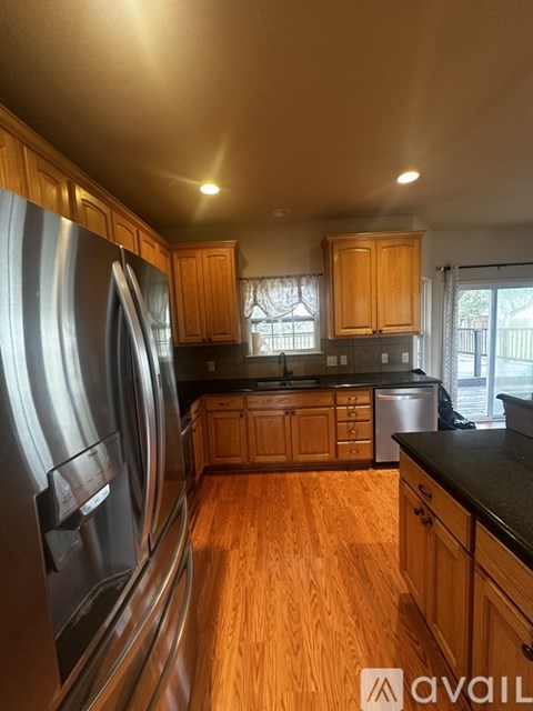 A kitchen with wooden cabinets and a stainless steel refrigerator.