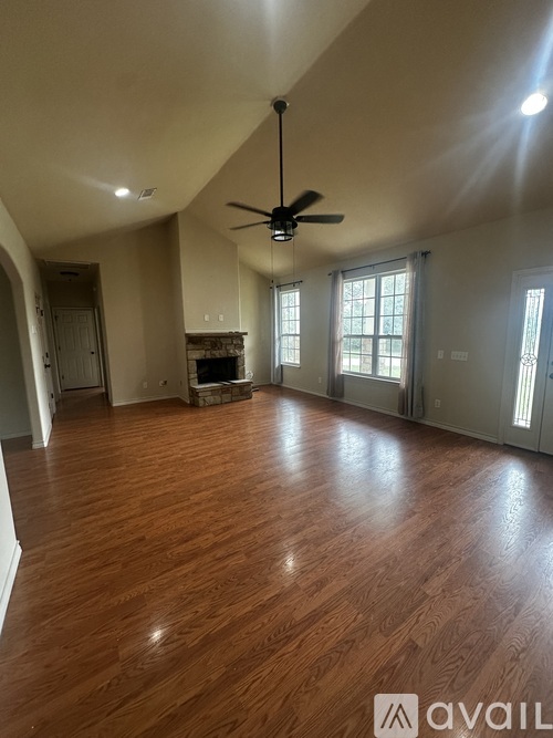 A spacious room with wooden flooring and a ceiling fan.